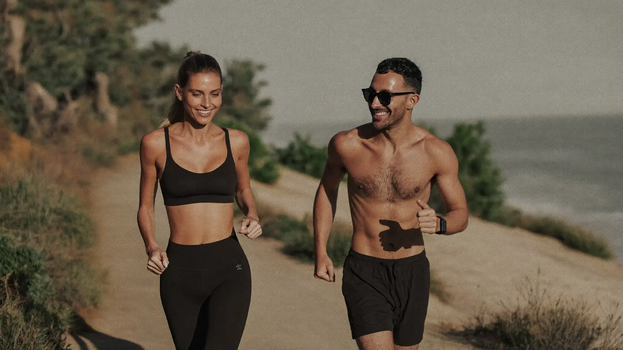 Two people jogging a coastal trail in morning light