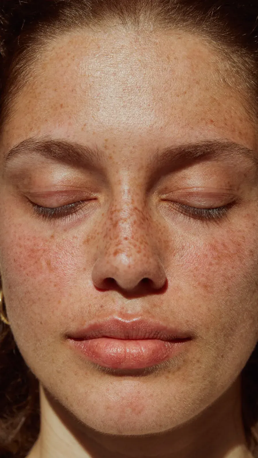 Close-up of a woman with freckles and closed eyes