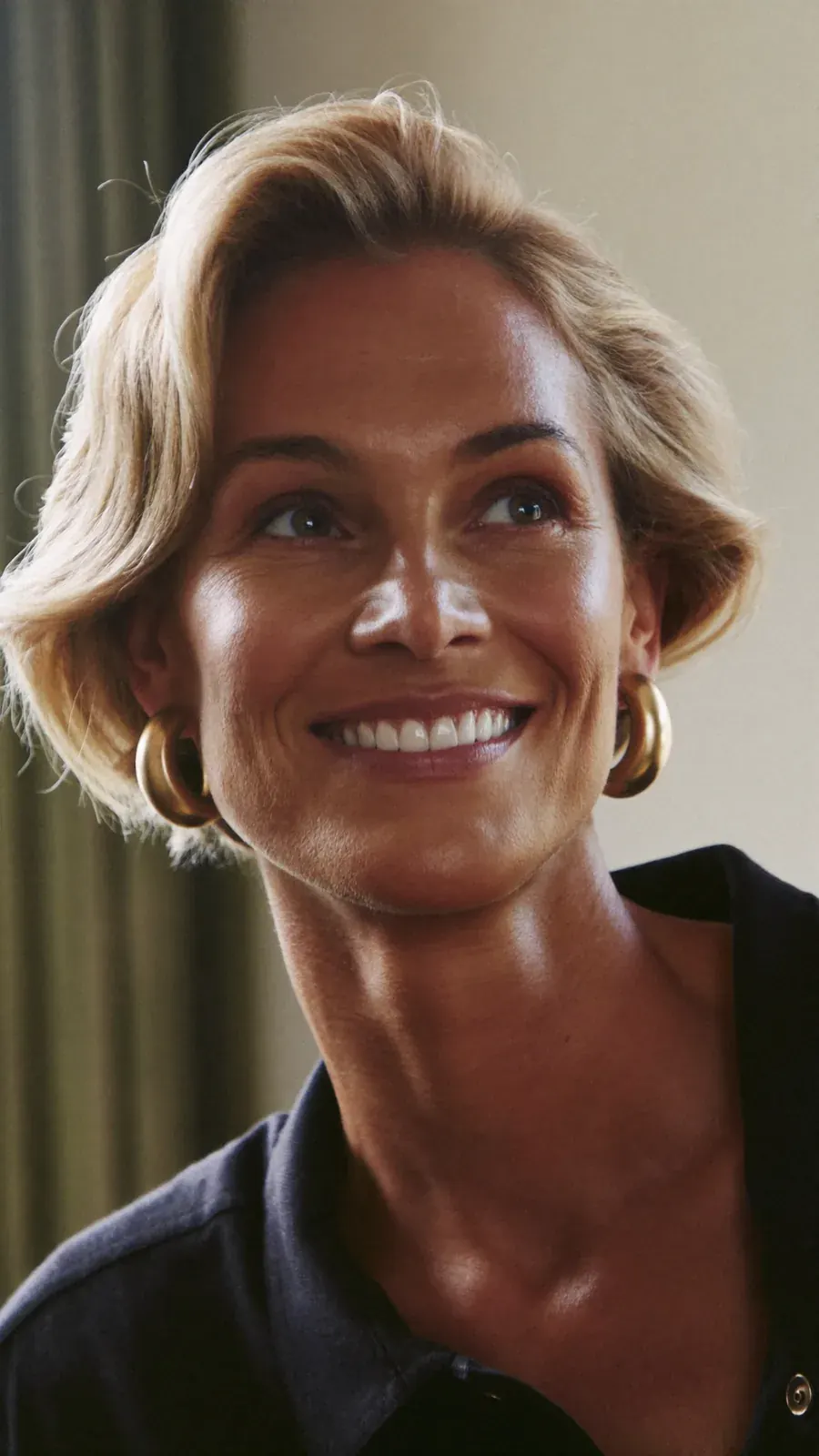 Smiling woman with short blonde hair and hoop earrings